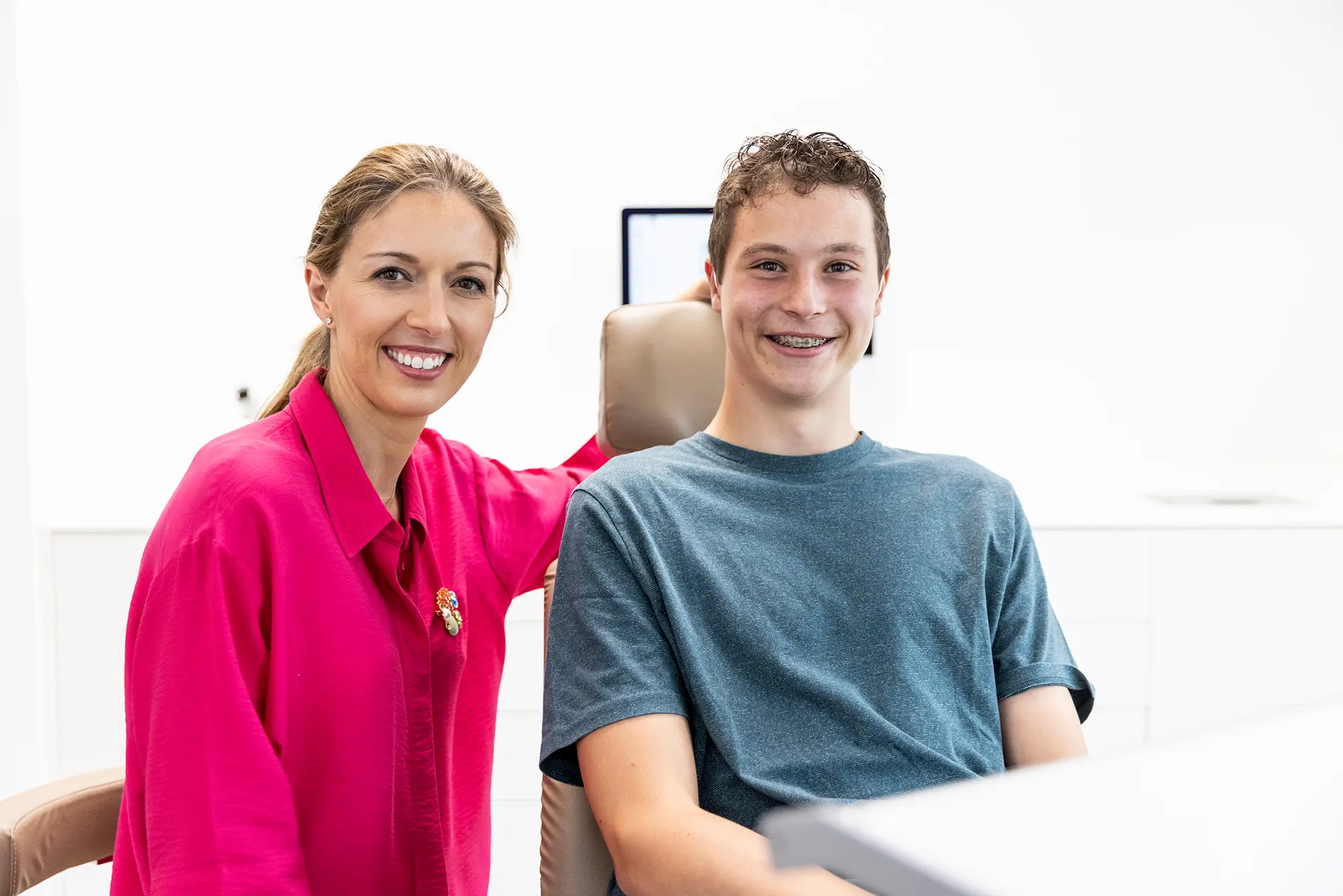 Junger Mann lacht und ist zurfrieden mit seiner kieferorthopädischen Behandlung in Wolfratshausen mit einer Metallbrackets.