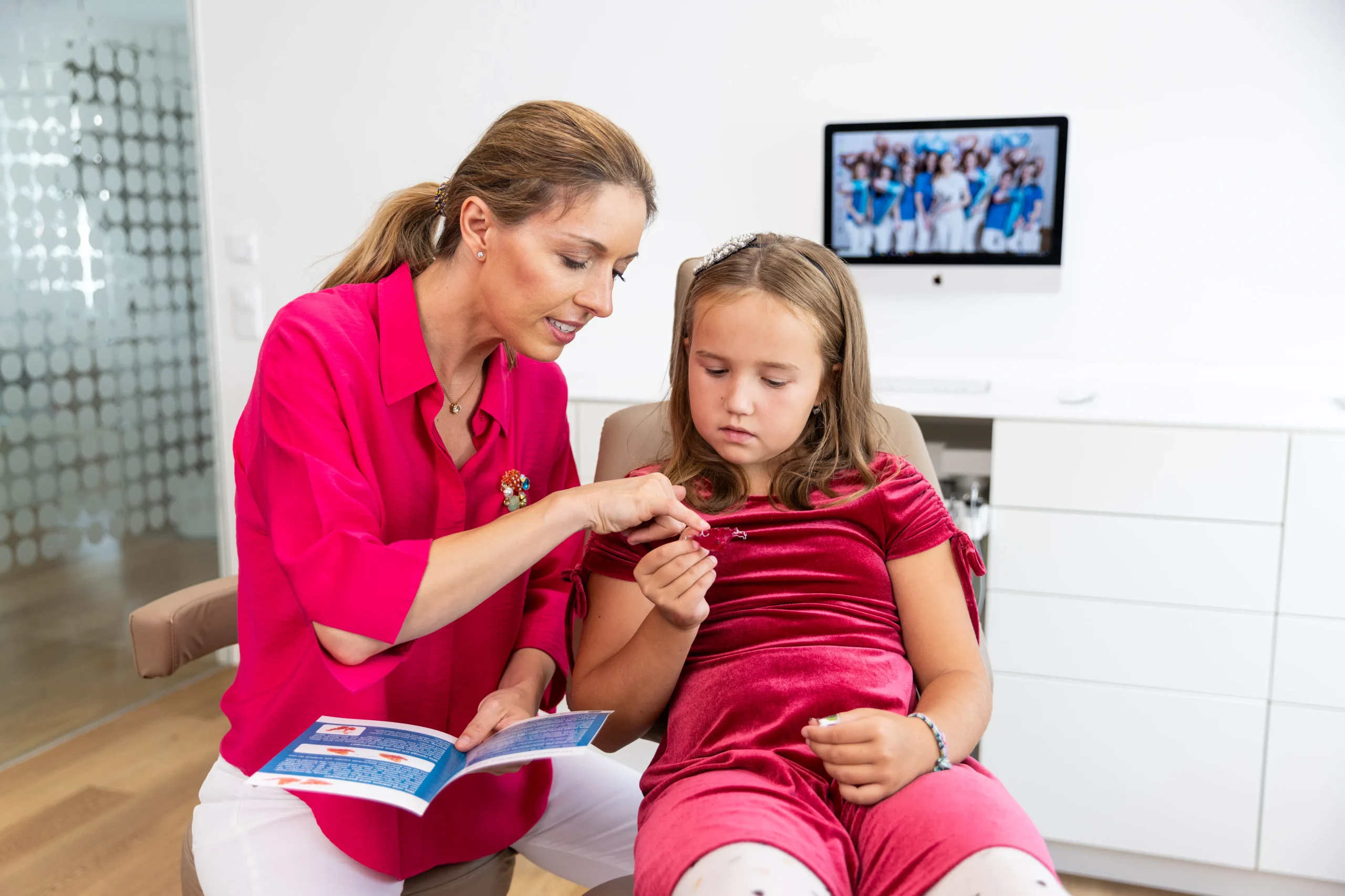 Reinigung Zahnspange, Tragezeit Zahnspange und Aktivierung der Dehnschraube wird dem Mädchen von Fachzahnärztin für Kieferorthopädie Dr. Jilek in ganzheitlicher Fachpraxis für Kieferorthopädie Prof. Jilek erklärt