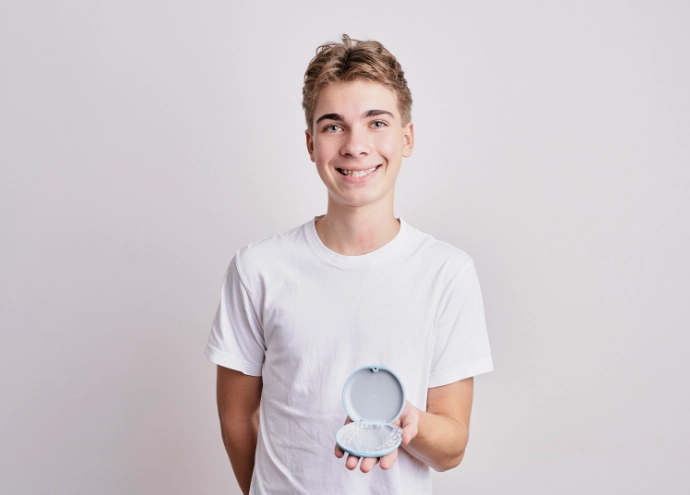 hübscher Junge mit tollen Zähnen und Invisalign in seinen Händen