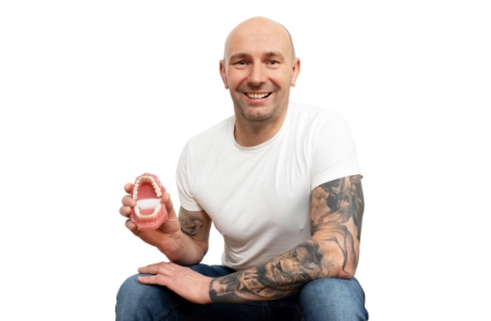 Erwachsener hält Modell mit unsichtbarere Zahnspange an Innenfläche der Zähnen als diskrete Zahnspange für Erwachsene