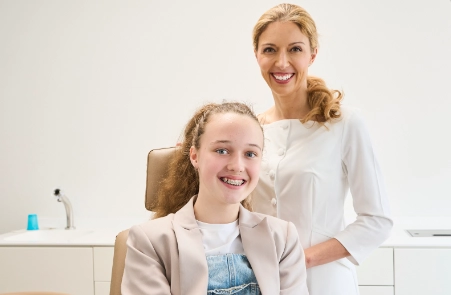 Kieferorthopädin kontrolliert den Behandlungsfortschritt bei einem Kontrolltermin feste Zahnspange Wolfratshausen bei einer Patientin mit fester Zahnspange bei komplexen Zahnfehlstellungen